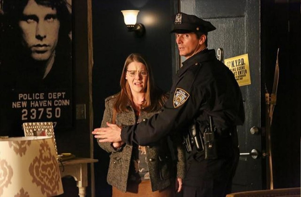 Un policier bloque l'accès à Amanda Lowery (Vivian Kerr).