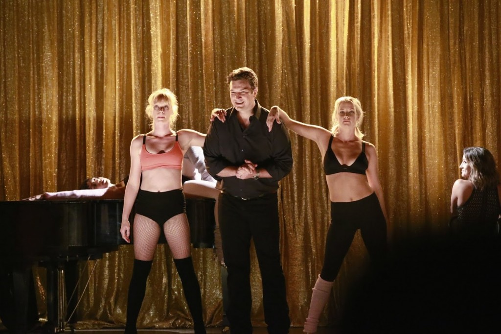 Castle (Nathan Fillion) sur scène avec des danseuses.